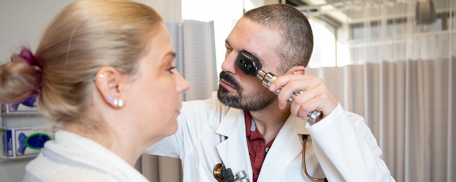 一名男护理研究生正在检查病人的眼睛.